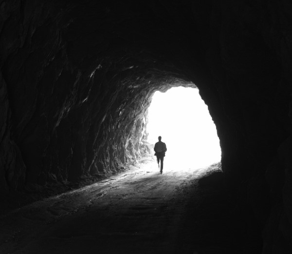 čovek na ulazu u mračnu pećinu iza kojeg je svetlost pred izborom