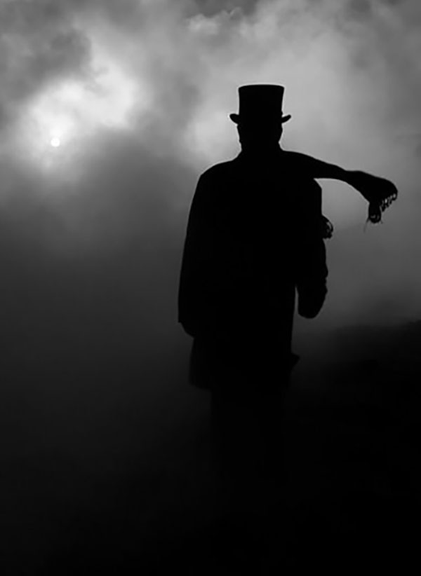 mračna silueta psihopate sa šeširom i šalom u magli